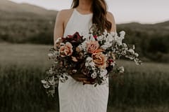 Outdoor micro wedding summer June bridal bouquet of peonies, belle epoque tulips, garden roses, iris, and flowering branches in warm desert neutral colors with flowing silk ribbon by Nectar and Root, Vermont wedding florist at a backyard wedding in Vermont.