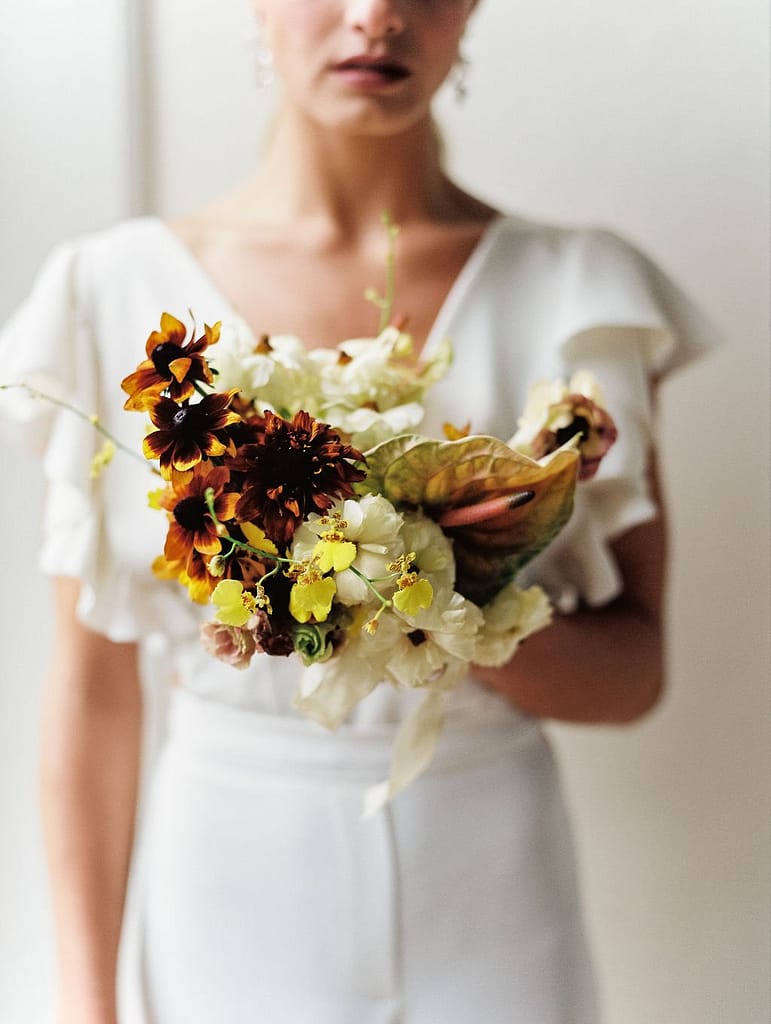A modern spring bridal bouquet of rudbeckia, orchids, and anthurium in a warm neutrals palette by Nectar and Root, a Vermont wedding florist.