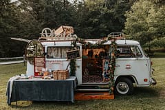 Vintage photo booth bus decorated with fall hanging garland installation of September foliage by Nectar and Root, Vermont wedding florist at Edson Hill in Stowe, Vermont.