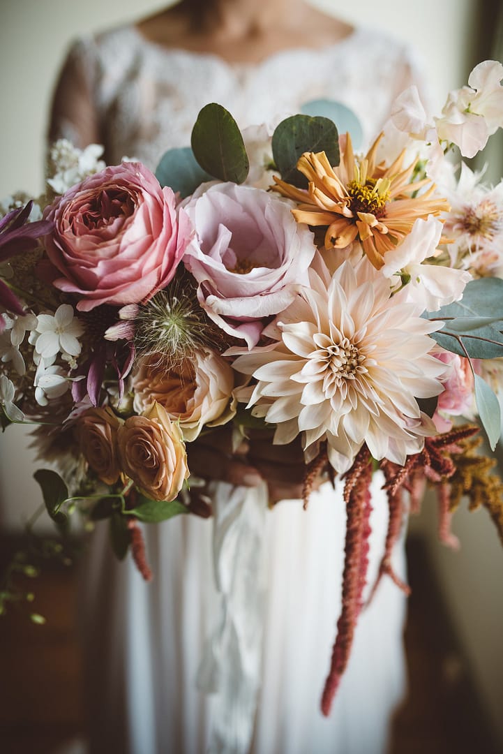 A lush summer bridal bouquet of September cafe au lait dahlias, eucalyptus, hanging amaranth and garden roses in a pastel color palette by Nectar and Root, a Vermont wedding florist.
