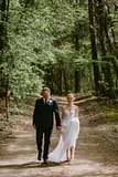 Bride and groom walking through trees by Nectar and Root, Vermont wedding florist at Shelburne Coach Barn in Shelburne, Vermont.