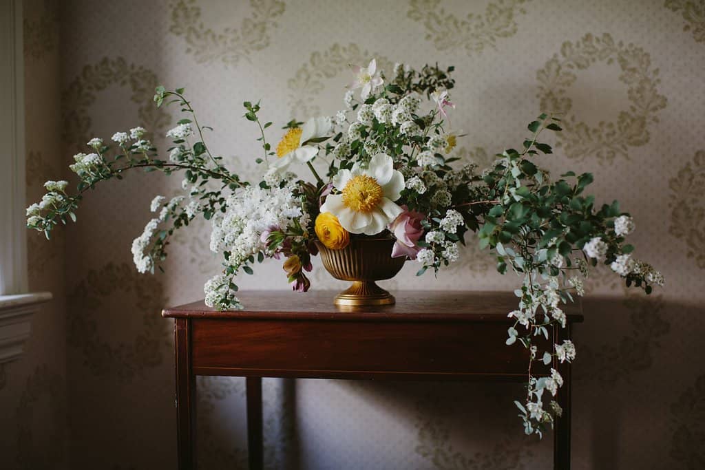 Centerpiece of peonies, ranunculus, hellebores and spirea by Nectar and Root, Vermont wedding florist at Shelburne Coach Barn in Shelburne, Vermont.