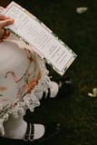 Flower girl holding floral ceremony program inspired by Nectar and Root, Vermont wedding florist at Shelburne Coach Barn in Shelburne, Vermont.