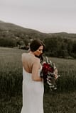Outdoor elopement bride with mountain views holding a June bridal bouquetby Nectar and Root, Vermont wedding florist at a backyard wedding in Vermont.