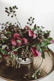 A modern spring reception centerpiece in a moody dark color palette atop a metal table table with a clear glass vase featuring eucalyptus and hellebores by Nectar and Root, Vermont wedding florist.