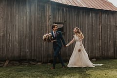 Bride and groom at romantic outdoor fall barn holding a modern September bridal bouquet of garden roses, hanging amaranth, sweet peas, dahlias, cosmos and zinnias by Nectar and Root, Vermont wedding florist at Edson Hill in Stowe, Vermont.