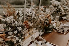 Boho reception centerpiece of dried flowers, peonies, roses, tulips, flowering branches and other June summer flowers in warm neutrals with tapered candles for outdoor elopement by Nectar and Root, Vermont wedding florist at a backyard wedding in Vermont.