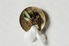 Textural boutonniere of berries, seed pods and greenery with white ribbon by Nectar and Root, Vermont wedding florist at Shelburne Museum in Shelburne, Vermont.