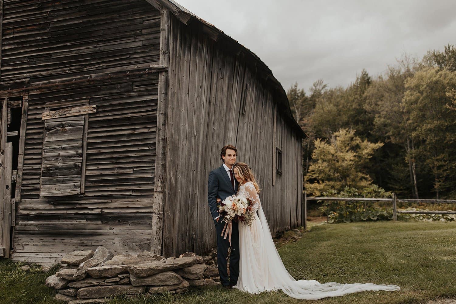 Bride and groom at romantic outdoor fall barn holding a modern September bridal bouquet of garden roses, hanging amaranth, sweet peas, dahlias, cosmos and zinnias by Nectar and Root, Vermont wedding florist at Edson Hill in Stowe, Vermont.